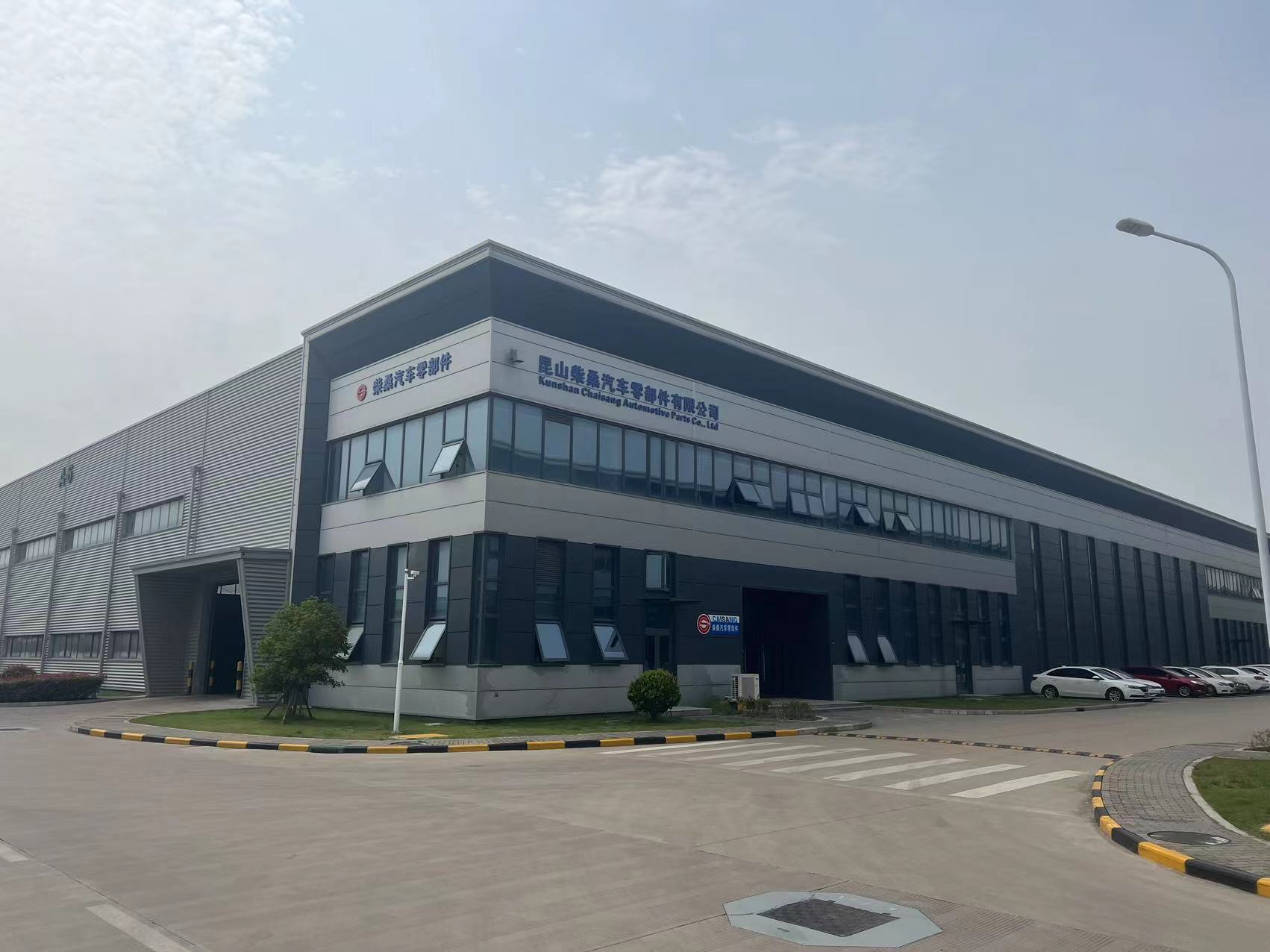 现代化汽车冲压件生产线设备，银色金属质感机器正在加工汽车零部件，车间明亮整洁，工人操作精密设备